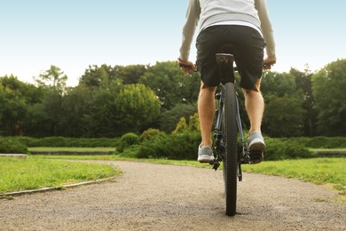 Photo of Man riding bicycle on road outdoors, back view. Space for text