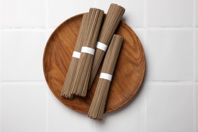 Photo of Uncooked buckwheat noodles (soba) on white tiled table, top view