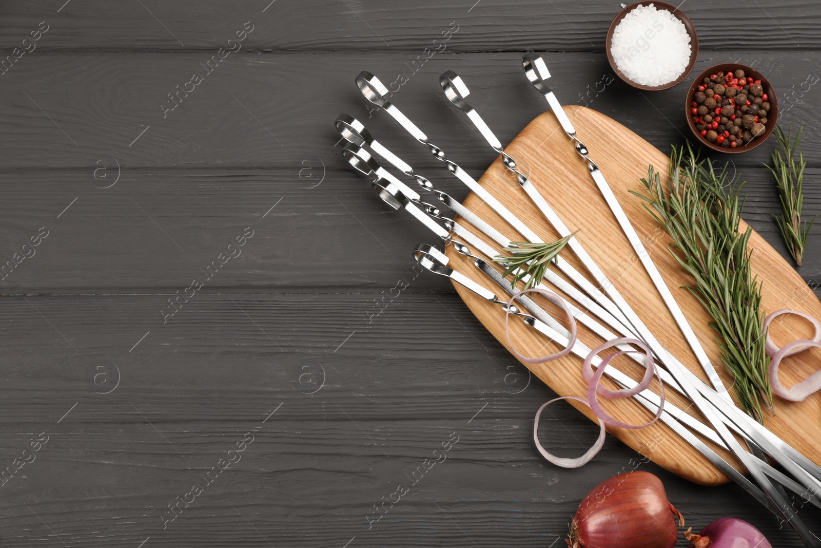 Photo of Flat lay composition with metal skewers on black wooden table. Space for text