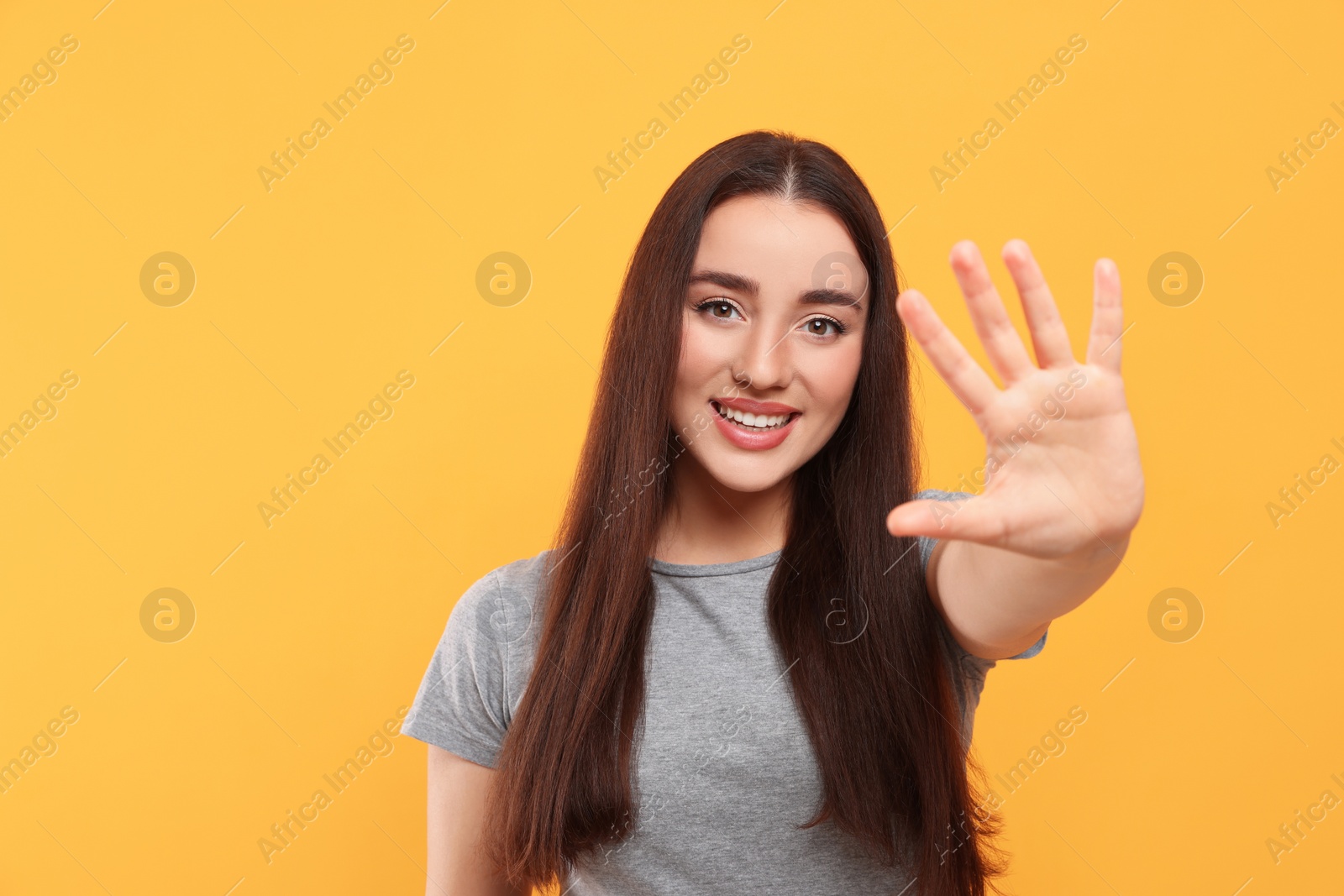 Photo of Happy woman giving high five on orange background, space for text