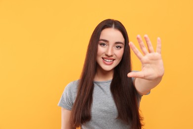 Photo of Happy woman giving high five on orange background, space for text