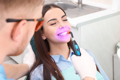 Photo of Professional dentist working with patient in modern clinic. Teeth whitening