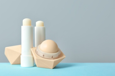 Photo of Hygienic lipsticks and balms on table against grey background