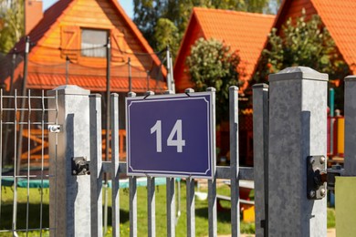 Photo of Plate with house number fourteen hanging on iron fence outdoors