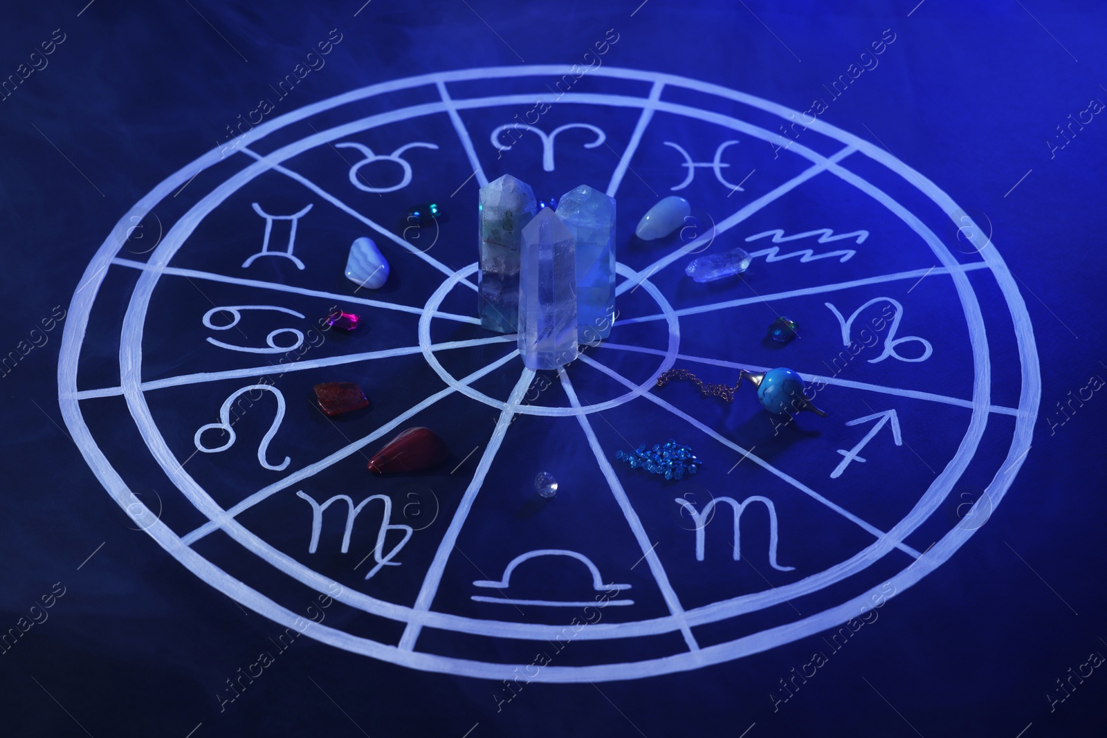 Photo of Natural stones for zodiac signs and drawn astrology chart on dark blue background