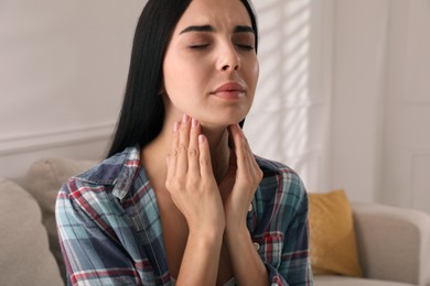 Young woman doing thyroid self examination at home