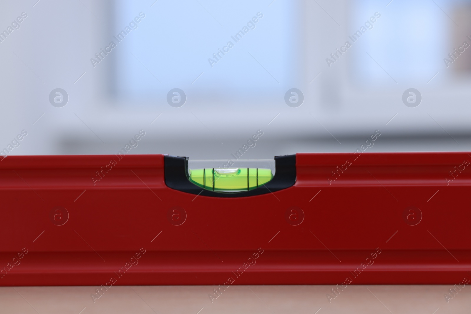 Photo of Red building level on wooden table indoors, closeup