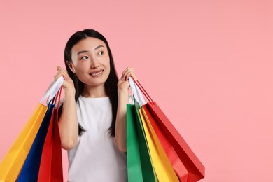 Photo of Smiling woman with shopping bags on pink background. Space for text