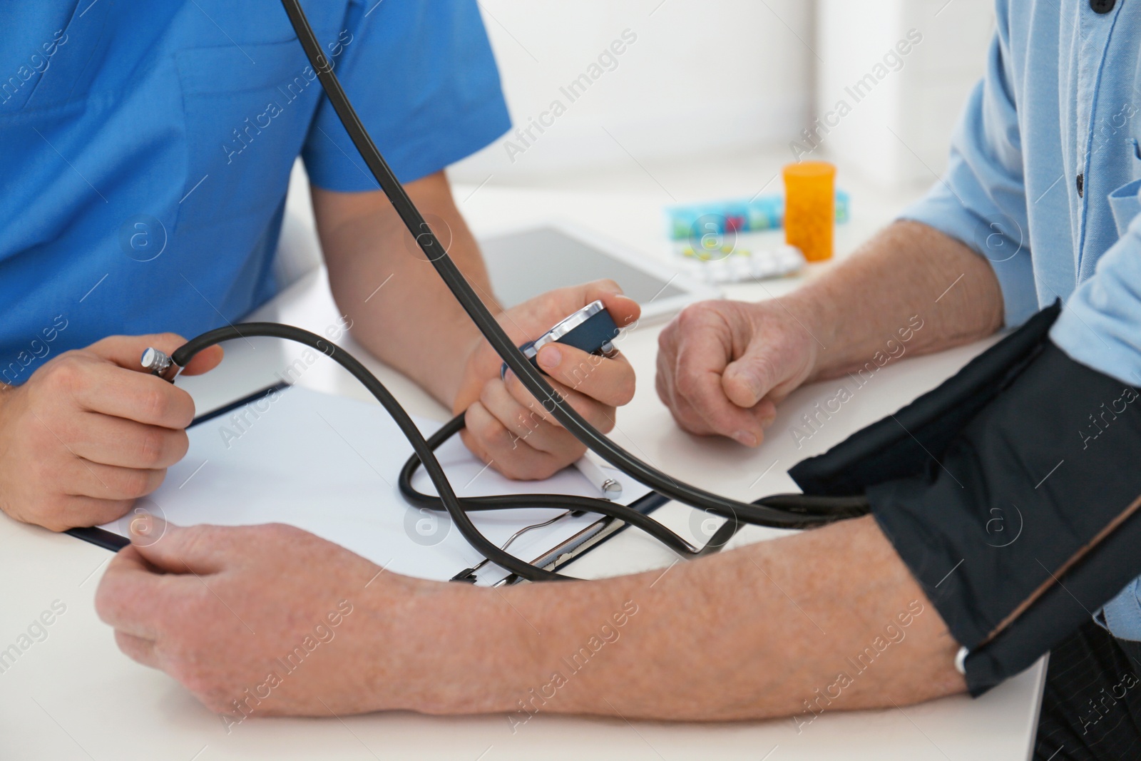 Photo of Doctor measuring blood pressure of senior patient in office, closeup