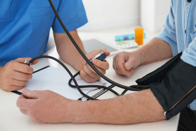 Photo of Doctor measuring blood pressure of senior patient in office, closeup