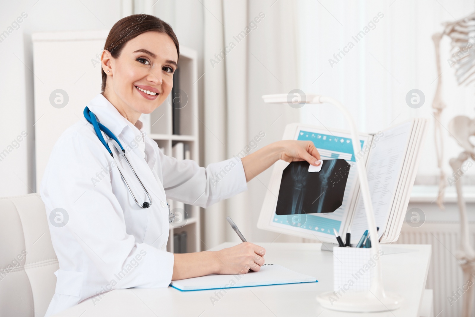 Photo of Orthopedist examining X-ray picture at desk in clinic