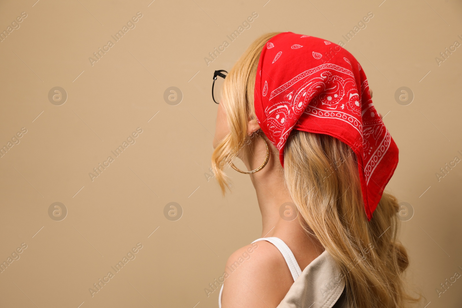 Photo of Young woman with stylish bandana on beige background. Space for text