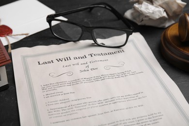 Photo of Last will and testament near glasses on black table, closeup