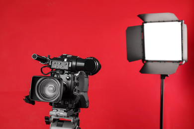 Photo of Professional video camera and lighting equipment on red background