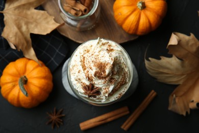 Photo of Flat lay composition with glass of pumpkin spice latte on black table