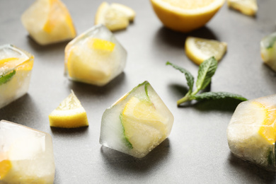 Ice cubes with lemon and mint on grey table, closeup
