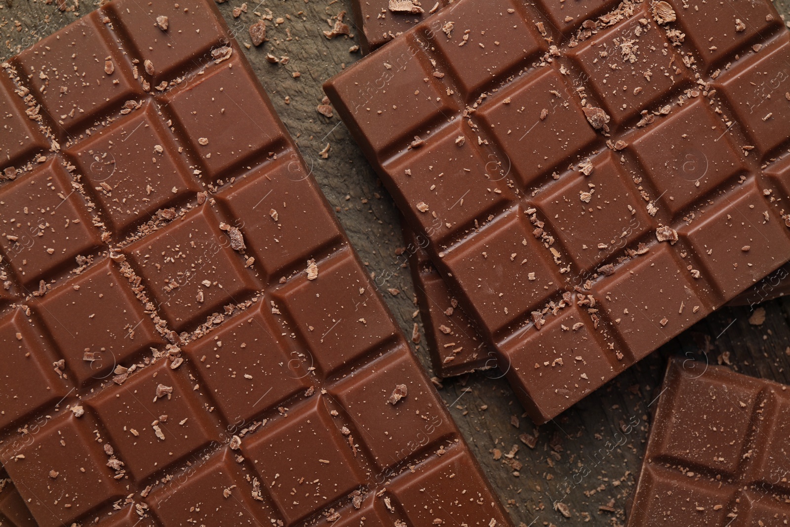 Photo of Tasty chocolate bars on wooden table, flat lay