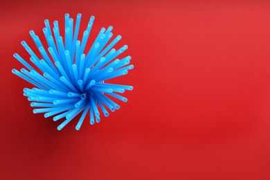 Photo of Light blue plastic drinking straws on red background, top view. Space for text