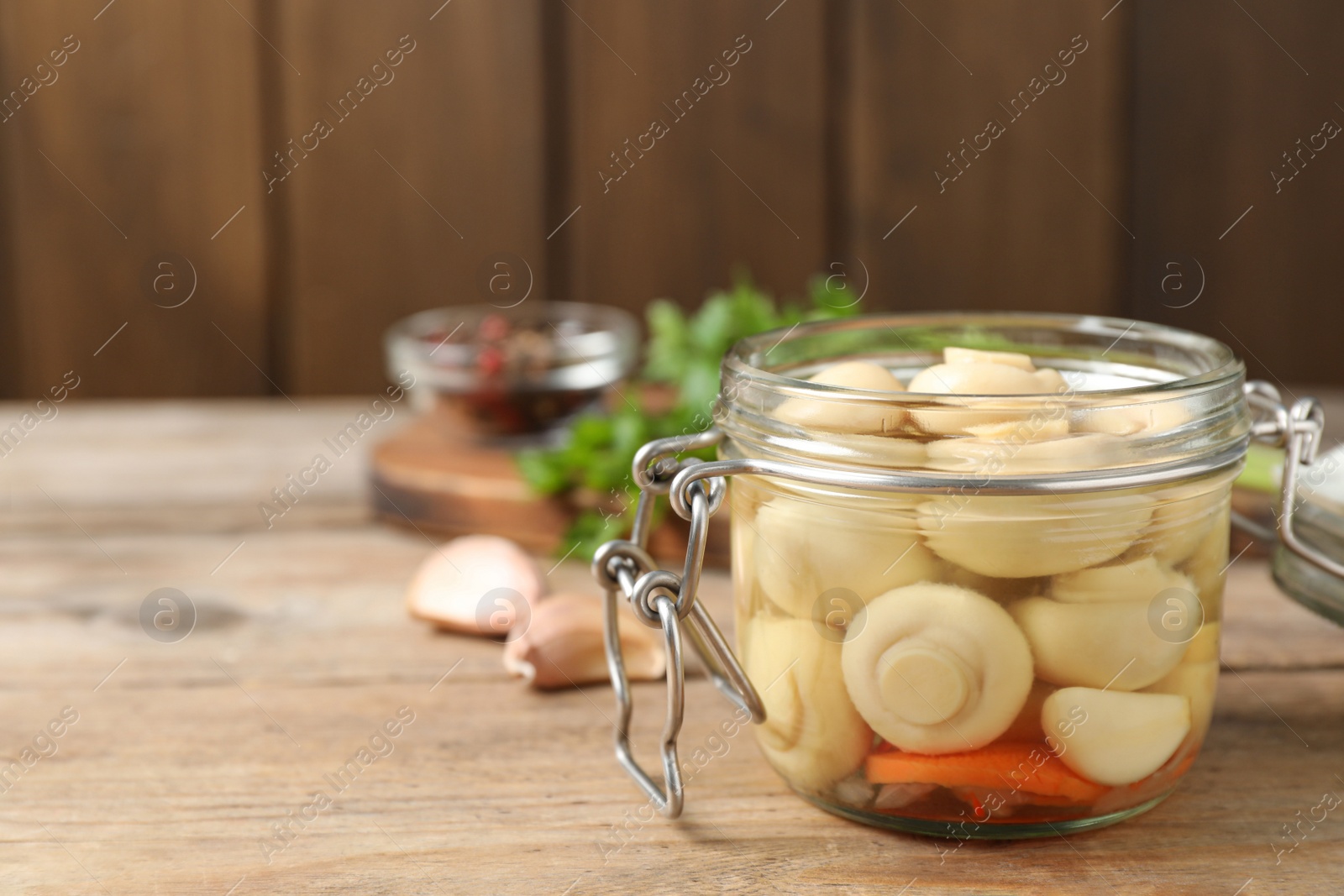 Photo of Jar with marinated mushrooms on wooden table, closeup. Space for text