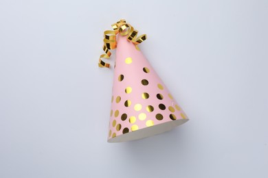 Photo of One pink party hat with serpentine streamers on light background, top view