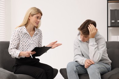 Psychologist working with teenage boy in office