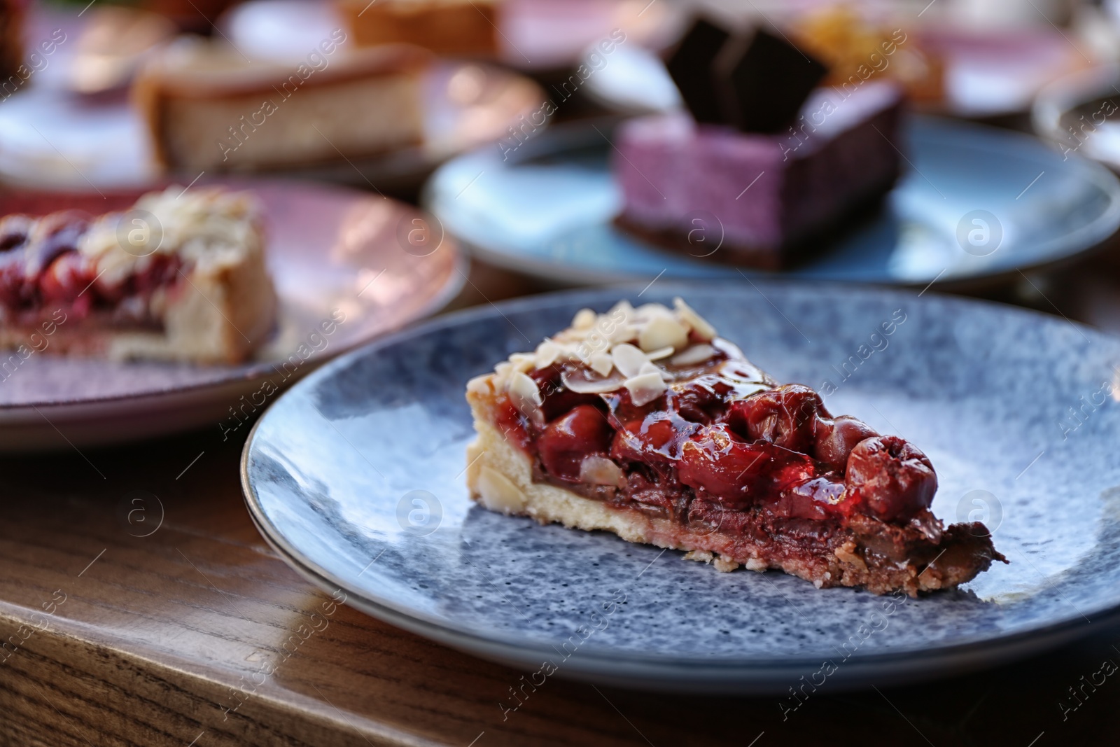 Photo of Plate with slice of cherry cake on wooden table