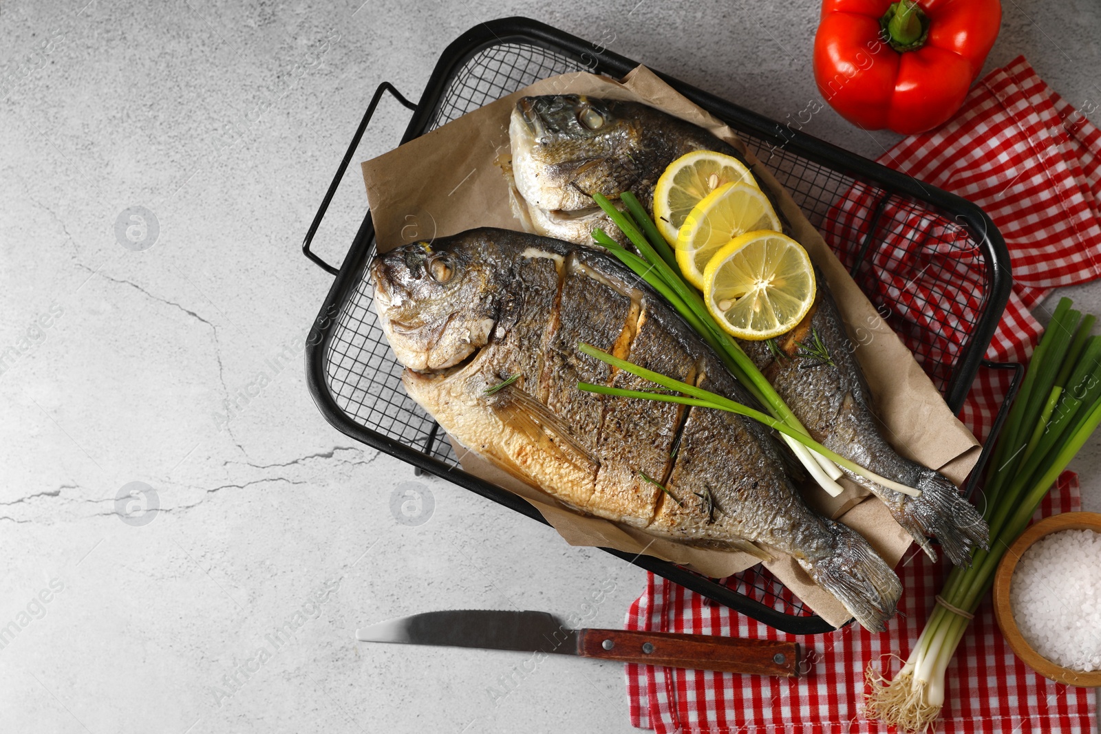 Photo of Seafood. Delicious baked fish served with green onion and lemon on light textured table, flat lay with space for text