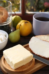 Photo of Tasty homemade butter, bread slices and tea on wooden table