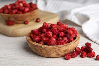 Fresh wild strawberries in bowl on white wooden table