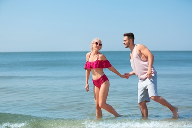 Happy young couple having fun at beach on sunny day