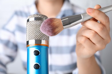 Photo of Woman making ASMR sounds with microphone and brush, closeup
