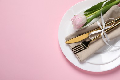 Photo of Stylish table setting with cutlery and tulip on pink background, top view. Space for text