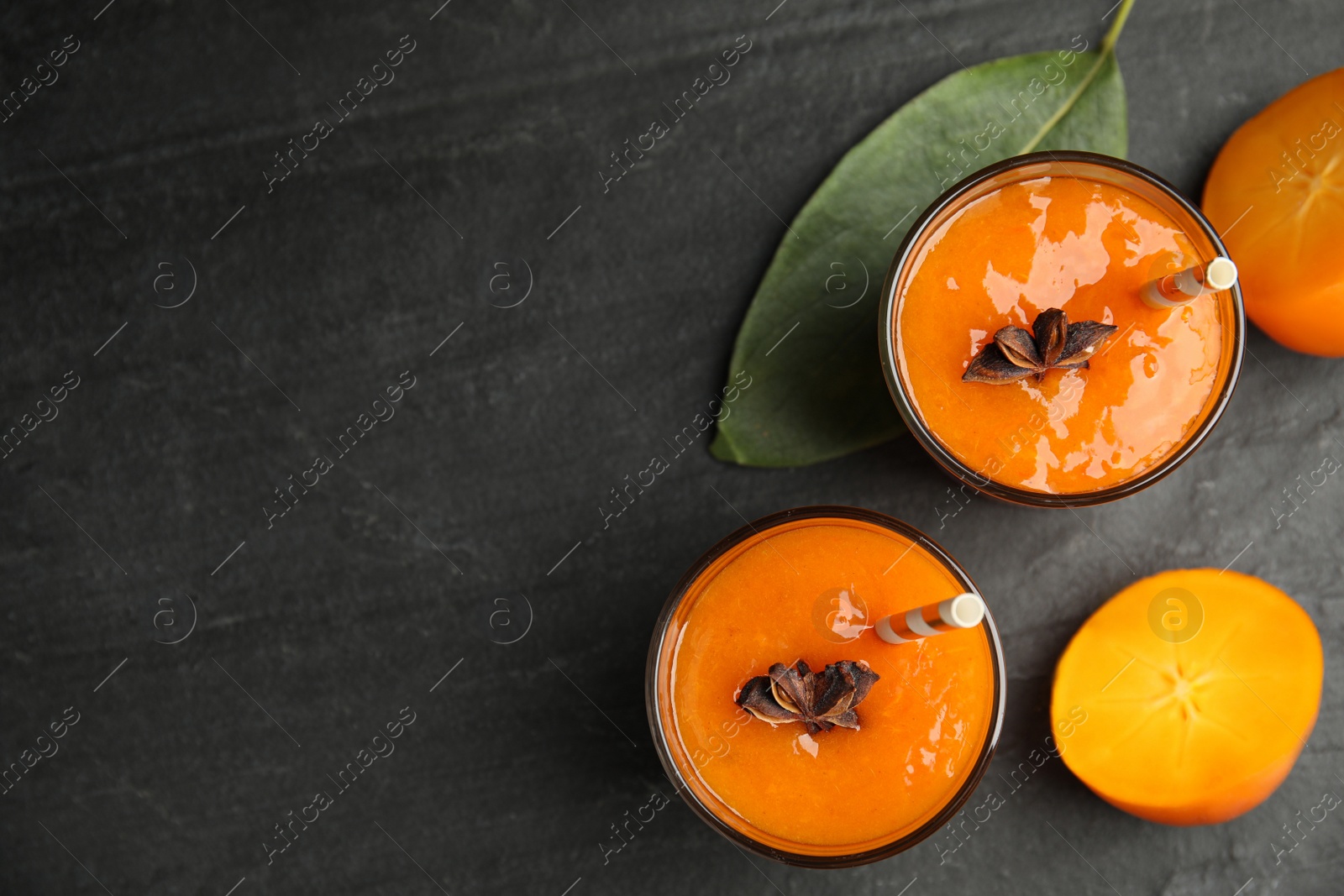 Photo of Tasty persimmon smoothie with anise and fresh fruits on black table, flat lay. Space for text