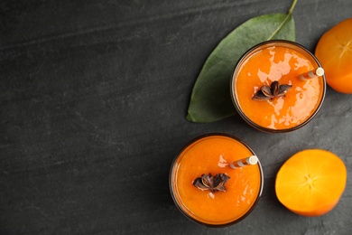 Photo of Tasty persimmon smoothie with anise and fresh fruits on black table, flat lay. Space for text