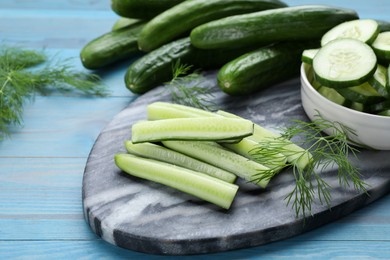 Photo of Fresh ripe cucumbers and dill on light blue wooden table, closeup