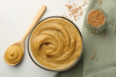 Photo of Tasty mustard sauce and dry seeds on white table, flat lay