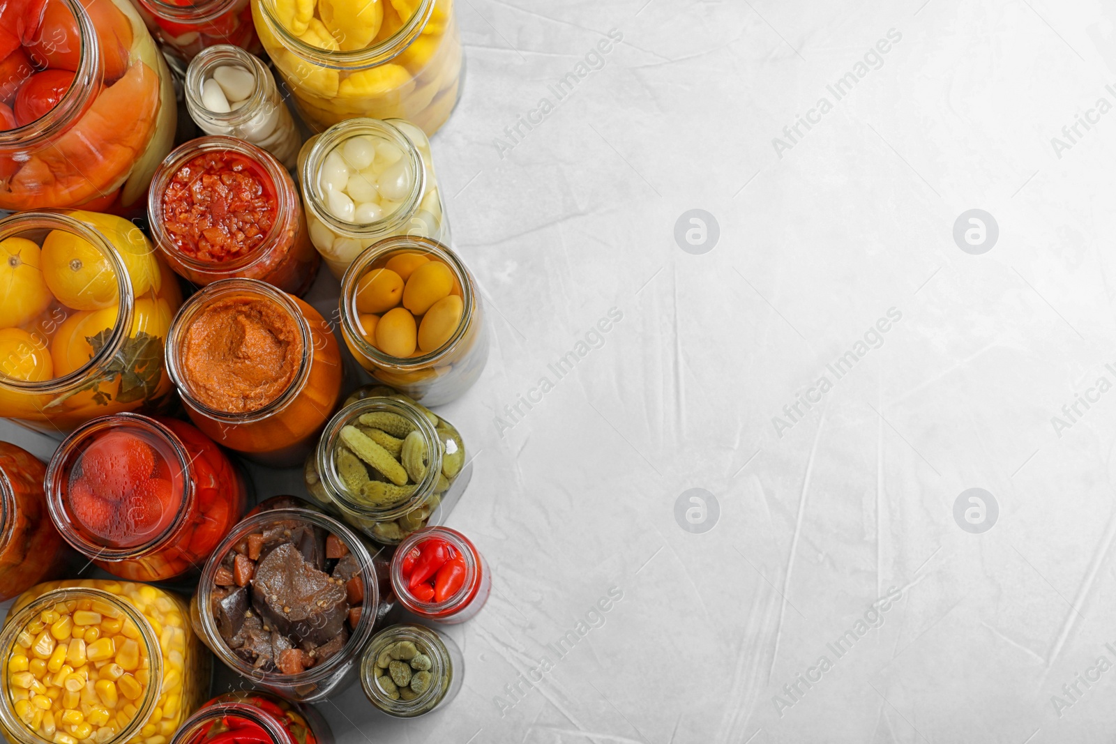 Photo of Jars with pickled vegetables on grey table, flat lay. Space for text