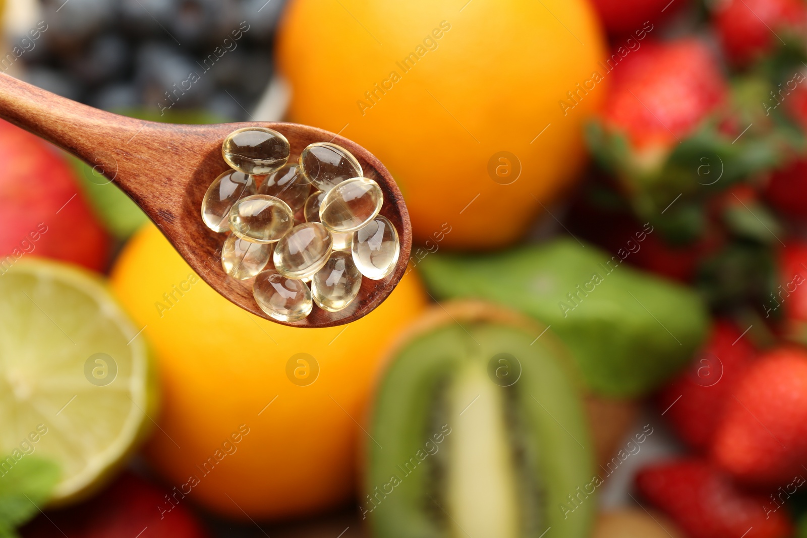 Photo of Vitamin pills in spoon over fresh fruits, top view. Space for text