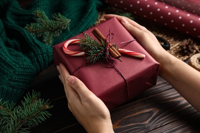 Photo of Woman with gift box at wooden table, closeup