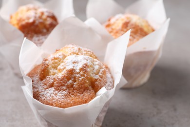 Photo of Delicious muffins with powdered sugar on grey table, closeup