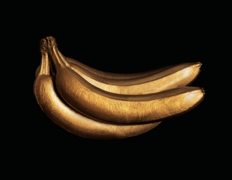 Photo of Bunch of gold painted bananas on black background