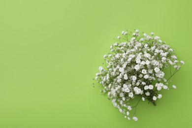 Photo of Beautiful bouquet of white gypsophila flowers on light green background, top view. Space for text