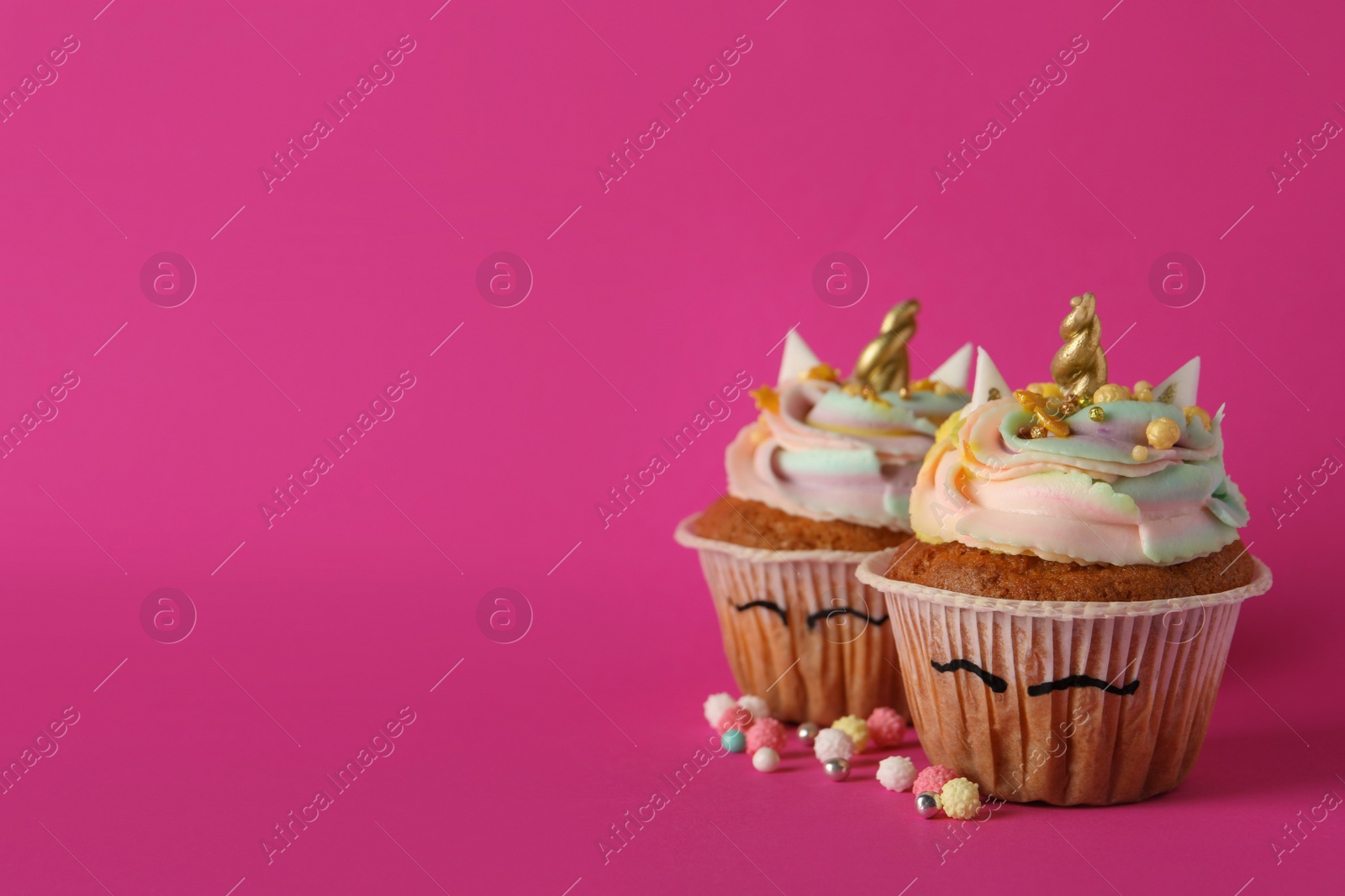 Photo of Cute sweet unicorn cupcakes on pink background, space for text