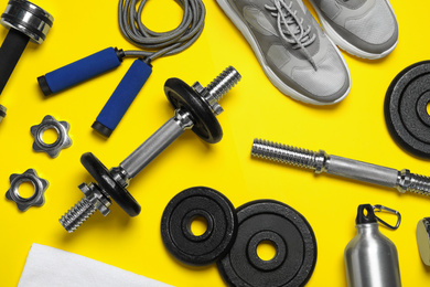 Photo of Gym equipment on yellow background, flat lay