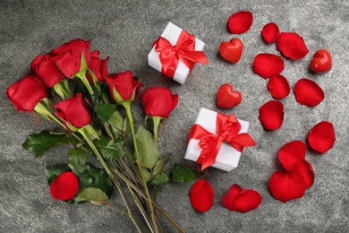 Photo of Flat lay composition with beautiful red roses and gift boxes on grey background. Valentine's Day celebration