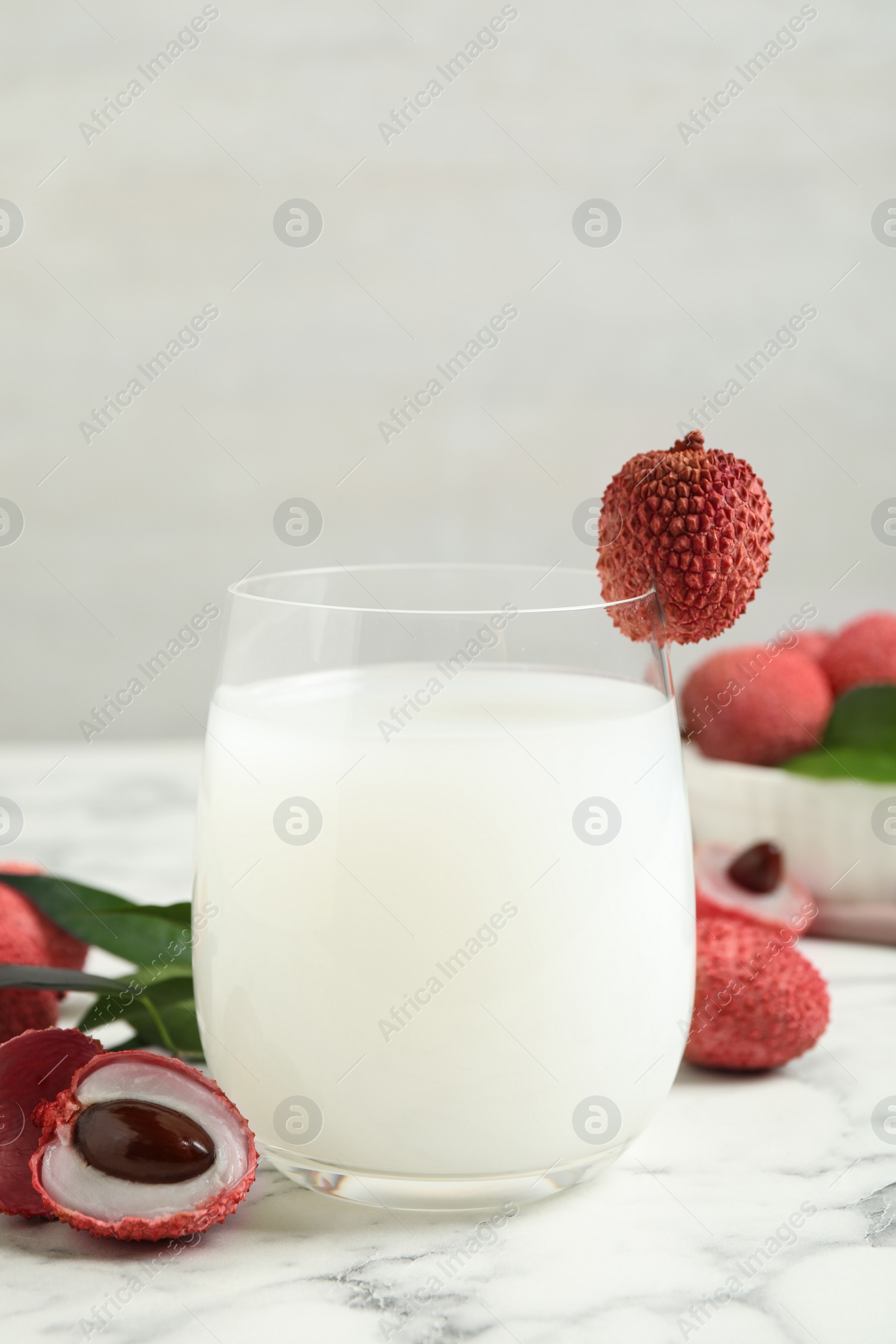 Photo of Lychee juice and fresh fruits on white marble table