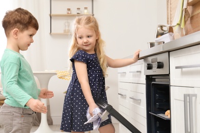 Cute children baking cookies in oven at home