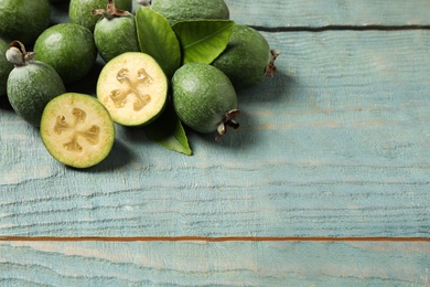 Photo of Fresh green feijoa fruits on blue wooden table, space for text