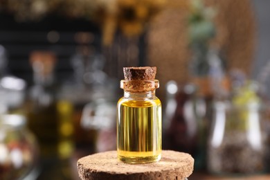 Bottle with herbal essential oils on blurred background. Space for text