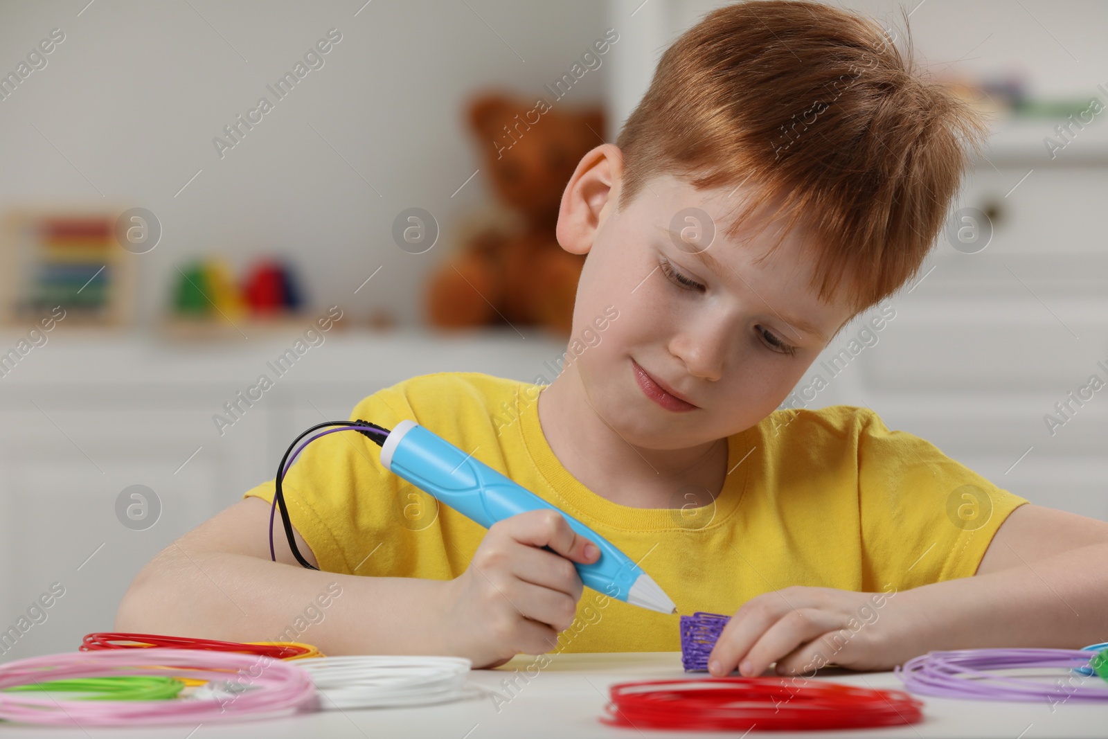 Photo of Boy drawing with stylish 3D pen at white table